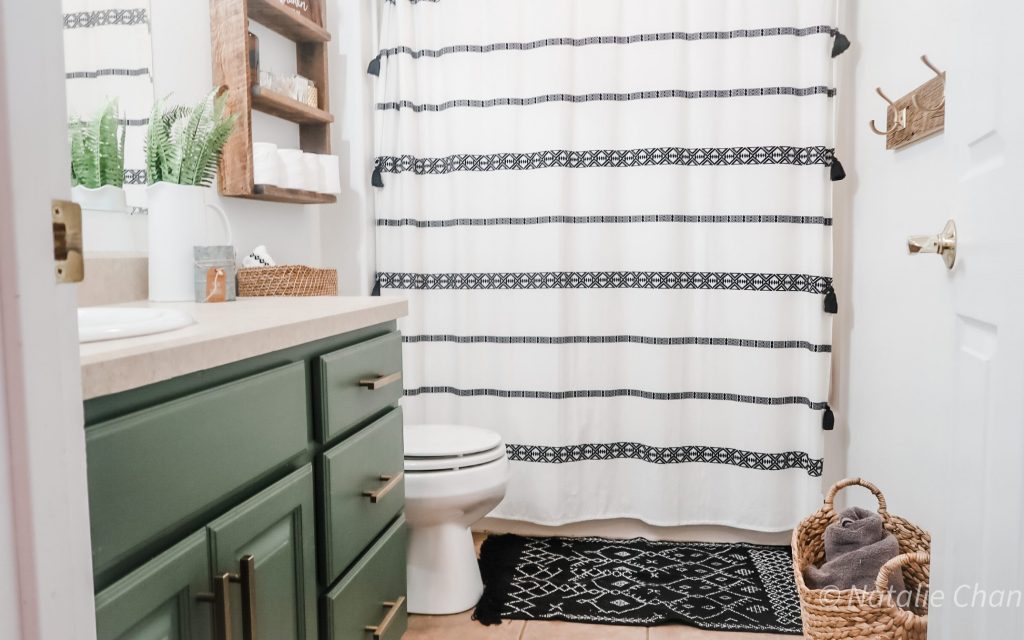 green bathroom cabinet and white and black shower curtain