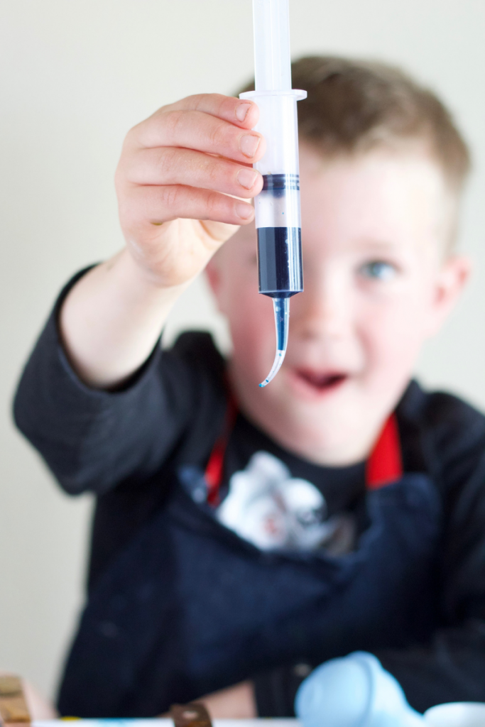 young boy holding a colorful dropper