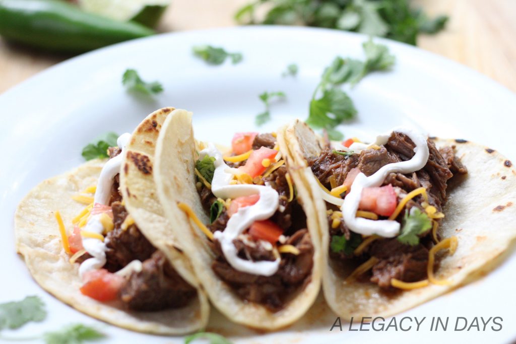 3 ingredient healthy beef tacos on a white plate with toppings and sour cream