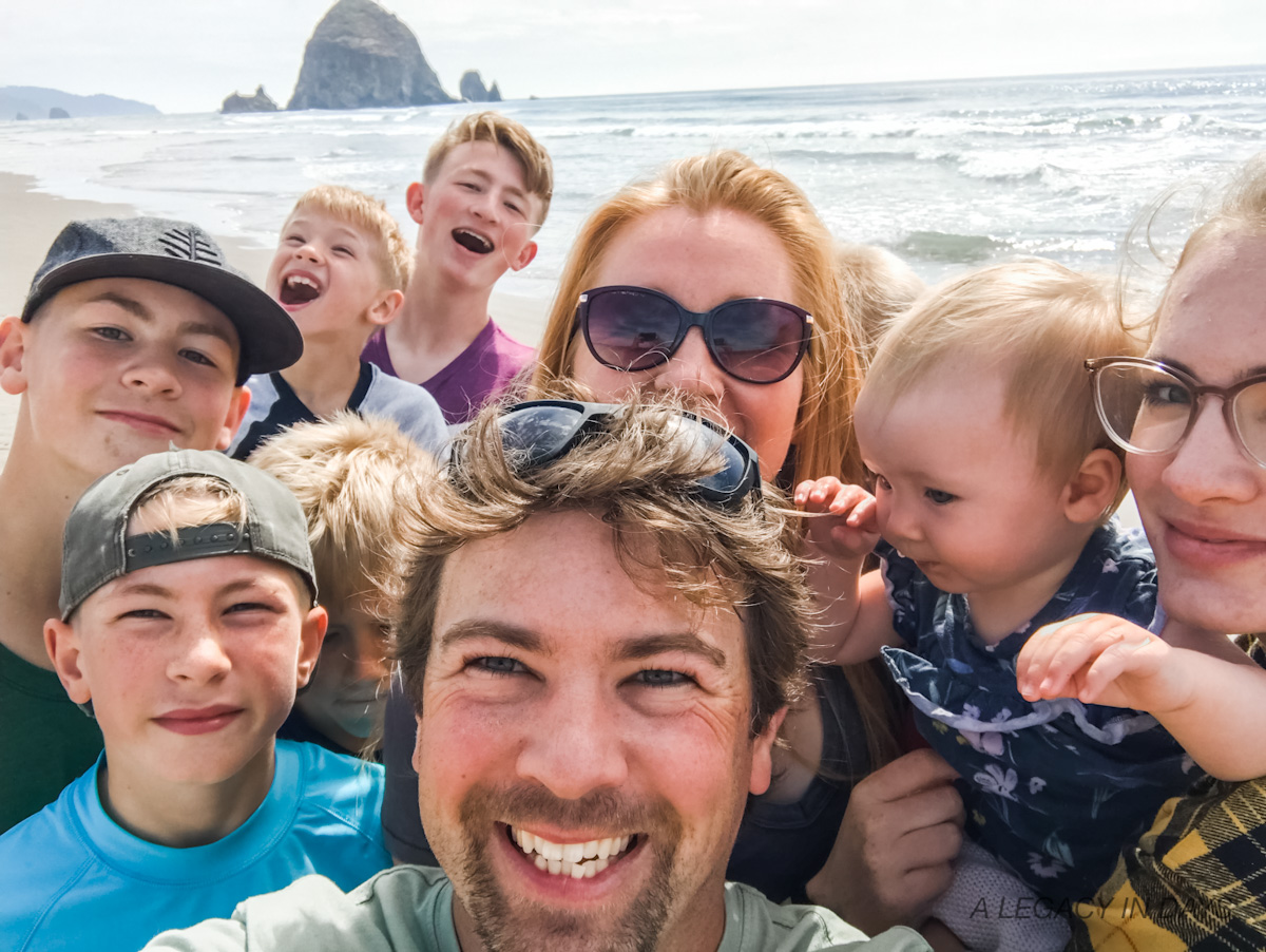 Family of 11 smiles for a selfie together at the ocean